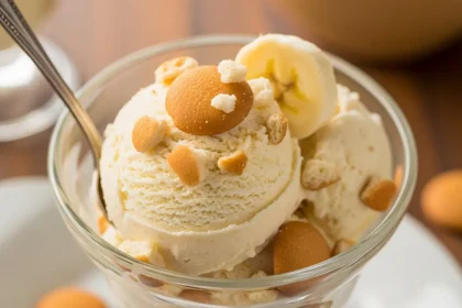 A scoop of homemade banana pudding ice cream with vanilla wafer crumbles in a glass.